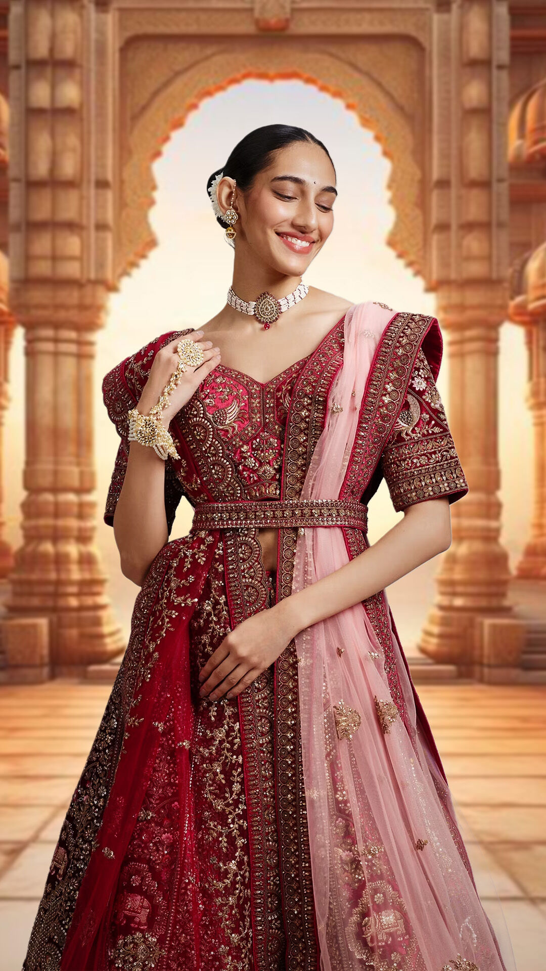 Woman flaunting a stylish red lehenga with a pink dupatta, layered with exquisite wedding jewelry for a statement look.